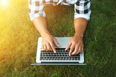 Man working with laptop outdoors on sunny day, closeup