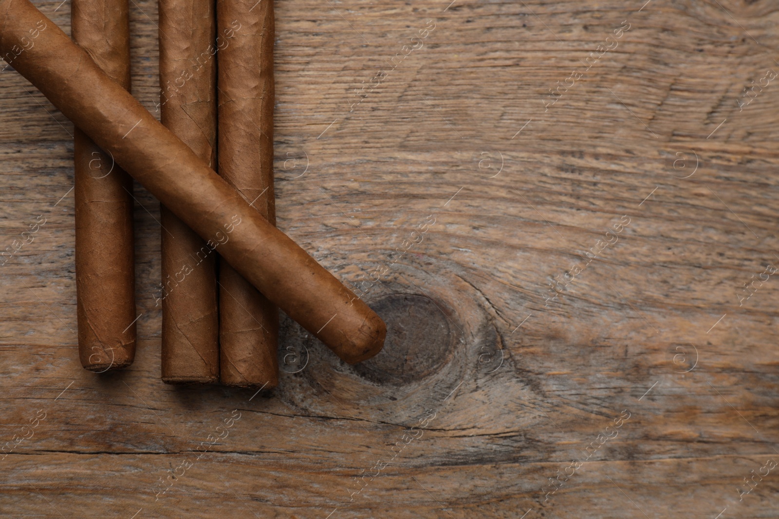 Photo of Many cigars on wooden table, flat lay. Space for text