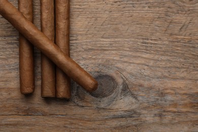 Photo of Many cigars on wooden table, flat lay. Space for text