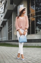 Photo of Young woman with stylish light blue bag on city street