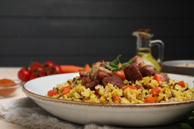 Delicious pilaf with meat and carrot on table, closeup. Space for text