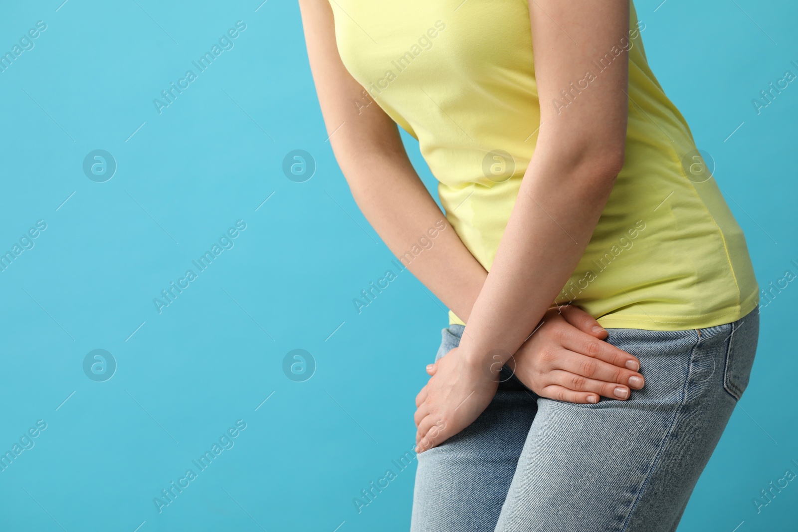 Photo of Woman suffering from cystitis on light blue background, closeup. Space for text