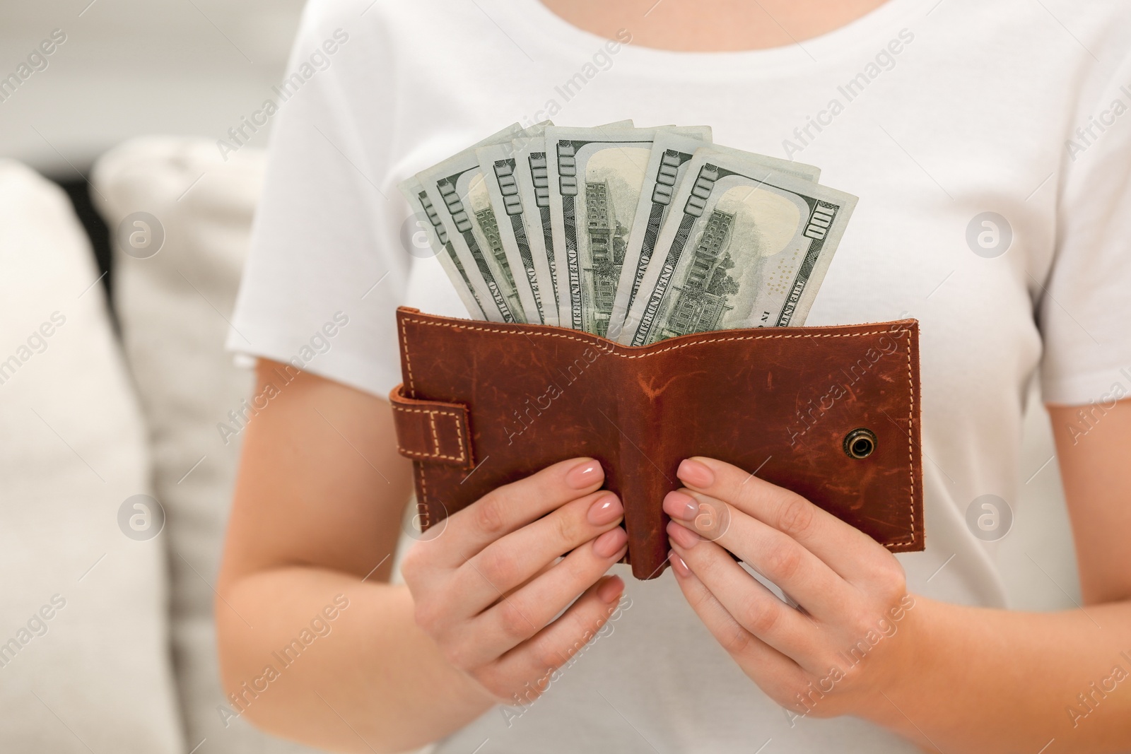 Photo of Woman holding brown leather wallet with dollar bills indoors closeup. Money exchange