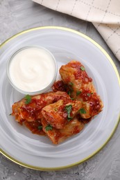 Photo of Delicious stuffed cabbage rolls served with sour cream on grey textured table, top view