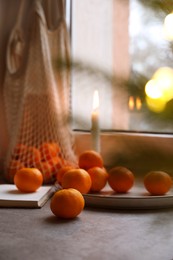 Fresh ripe tangerines and Christmas decor on grey table near window