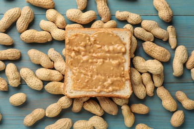 Photo of Delicious toast with peanut butter and nuts on light blue wooden table, flat lay