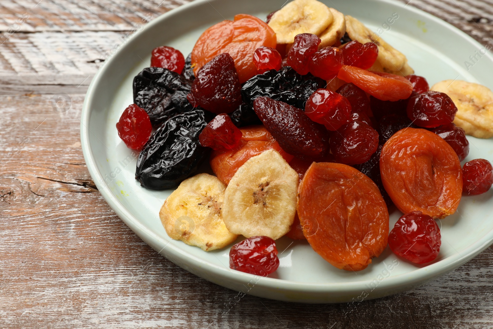 Photo of Mix of delicious dried fruits on wooden table, closeup