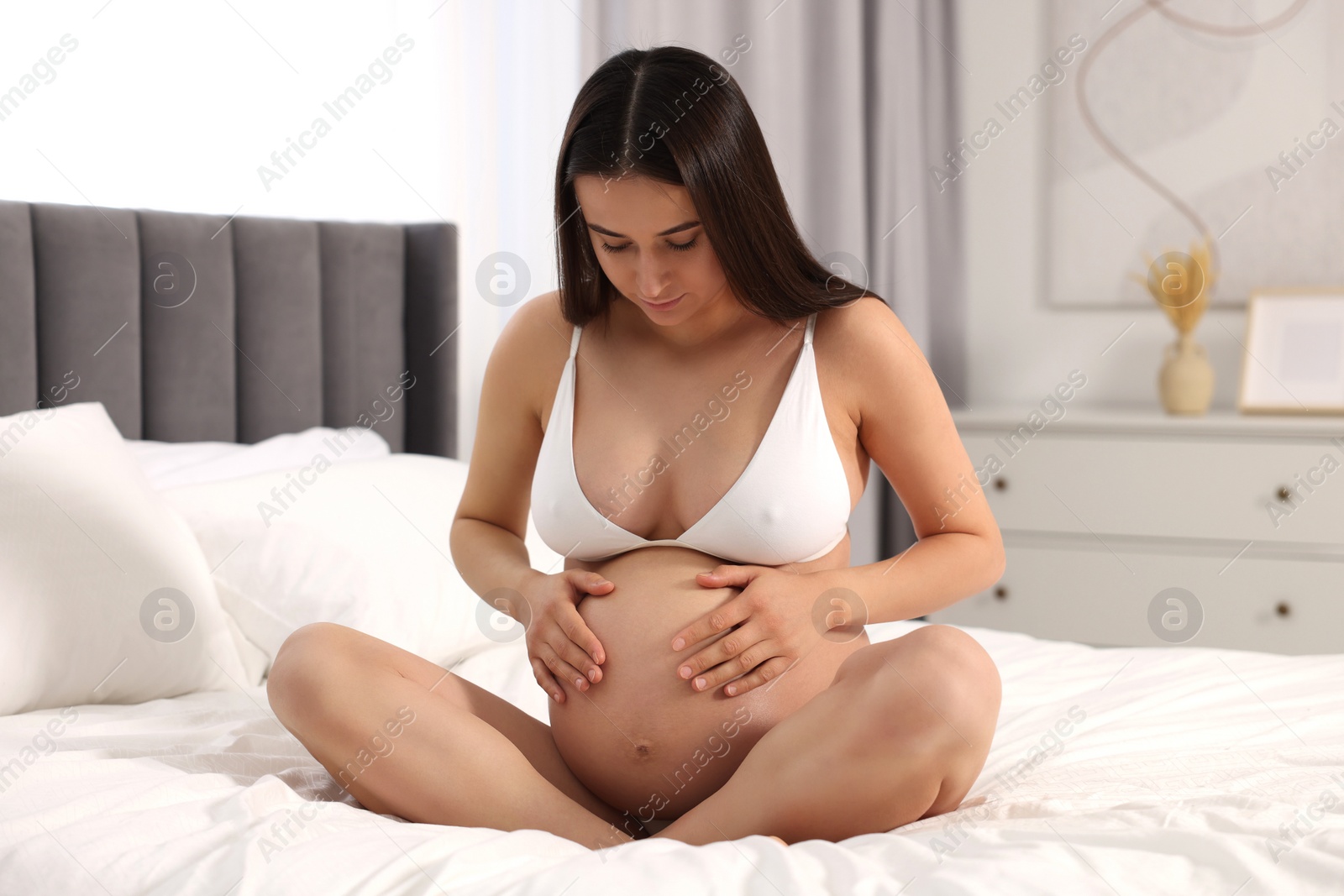 Photo of Beautiful pregnant woman in stylish comfortable underwear on bed at home