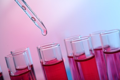 Dripping reagent into test tube with red liquid, closeup. Laboratory analysis