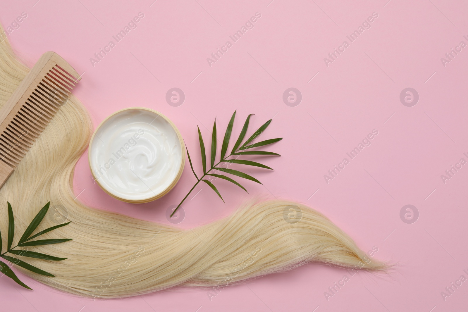 Photo of Lock of healthy blond hair, comb and cosmetic product on pink background, flat lay. Space for text