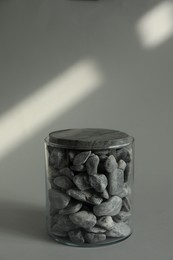 Photo of Presentation for product. Glass container with stones on light grey background. Space for text