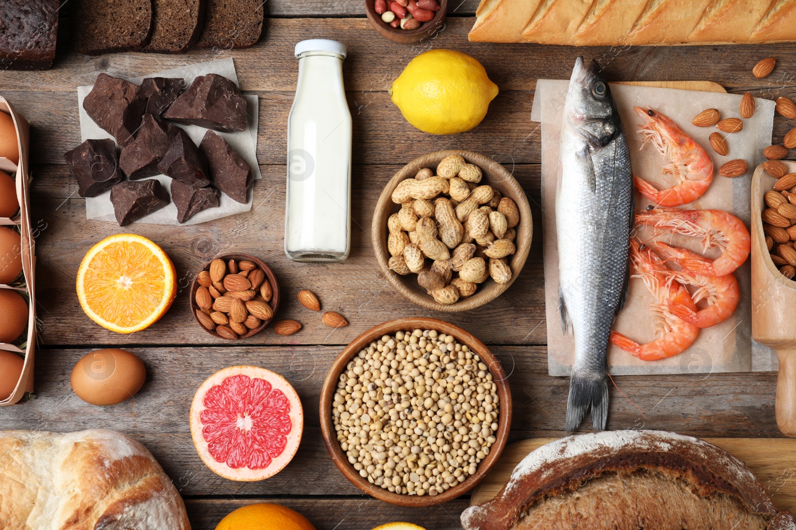 Photo of Flat lay composition of different products on wooden table. Food allergy concept