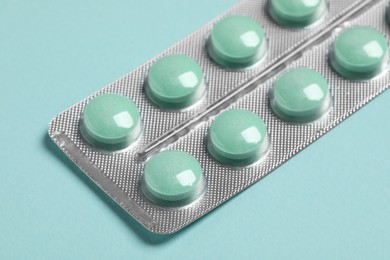 Pills in blister on turquoise background, closeup