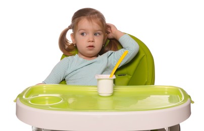 Cute little child eating tasty yogurt from plastic cup with spoon in high chair on white background
