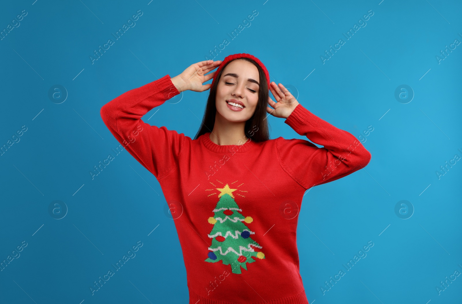 Photo of Young woman in Christmas sweater and hat on blue background