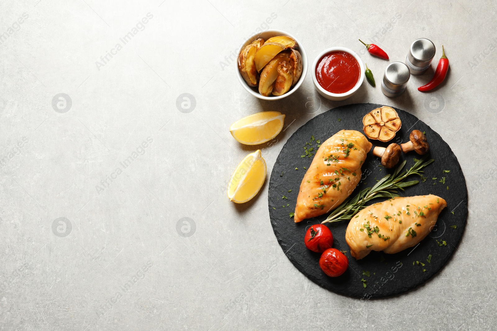 Photo of Fried chicken breasts served with sauce and garnish on grey background, flat lay. Space for text