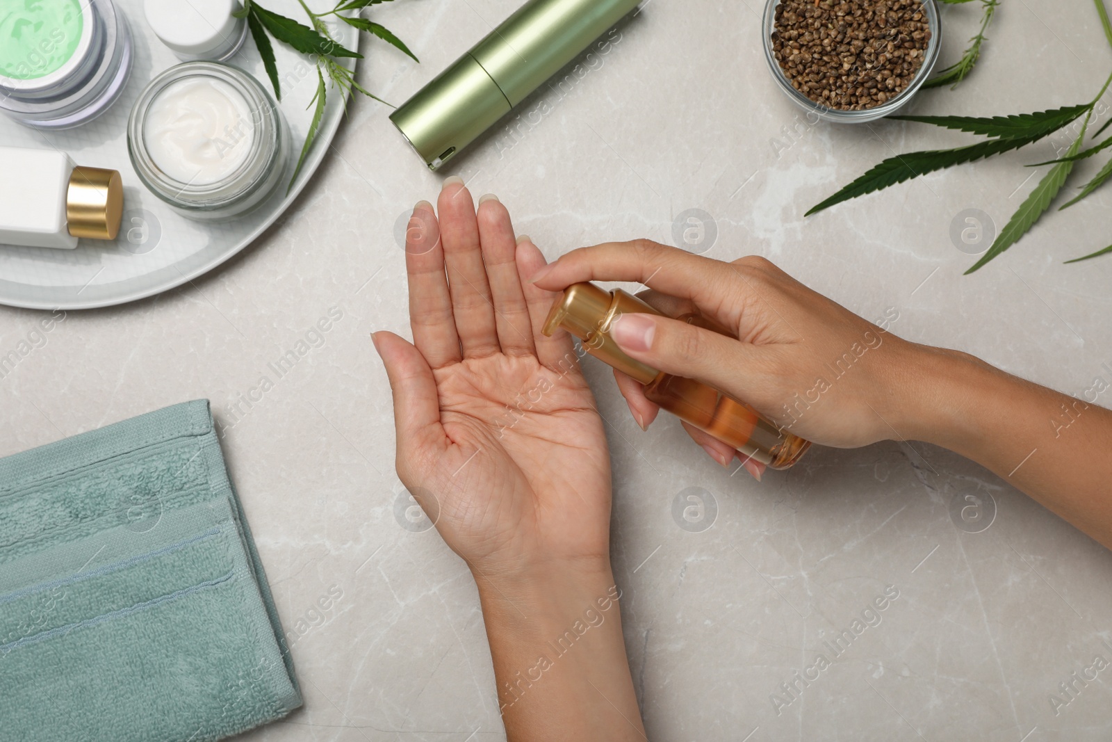 Photo of Woman applying hemp cosmetic product at light table, top view