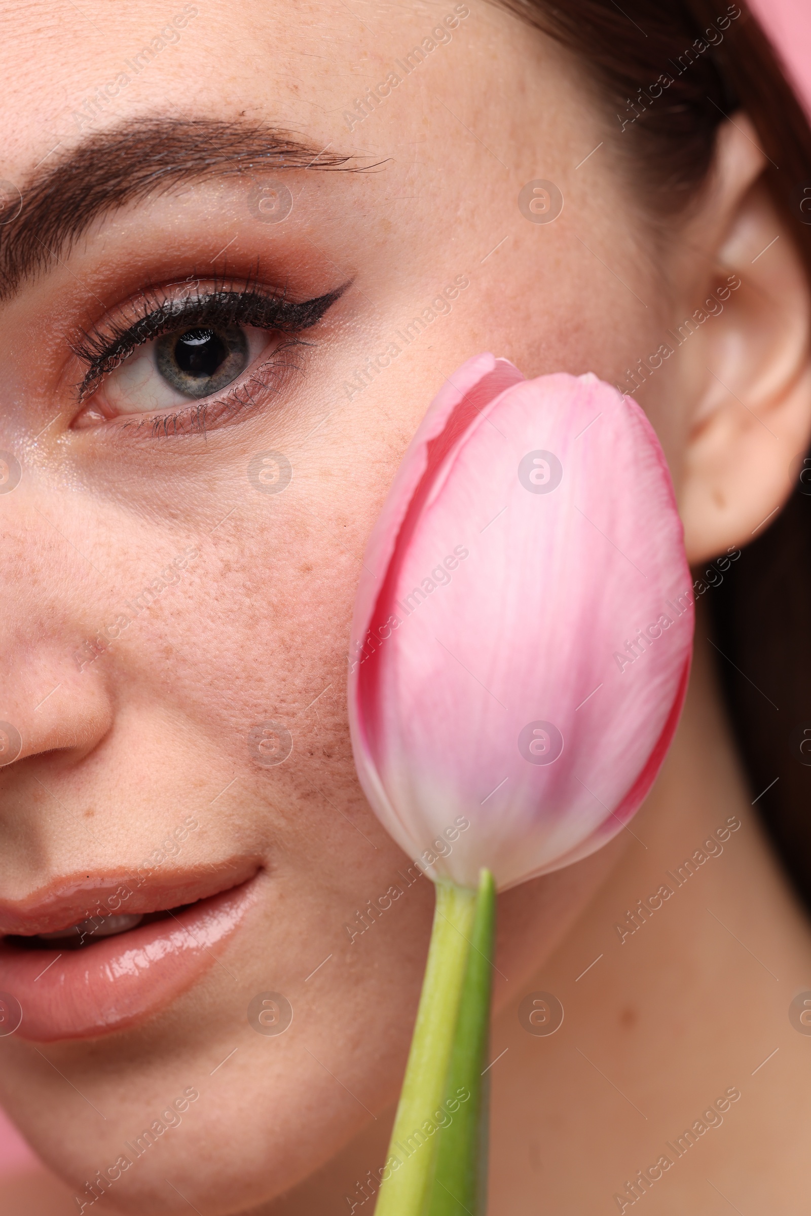 Photo of Beautiful woman with fake freckles and tulip, closeup