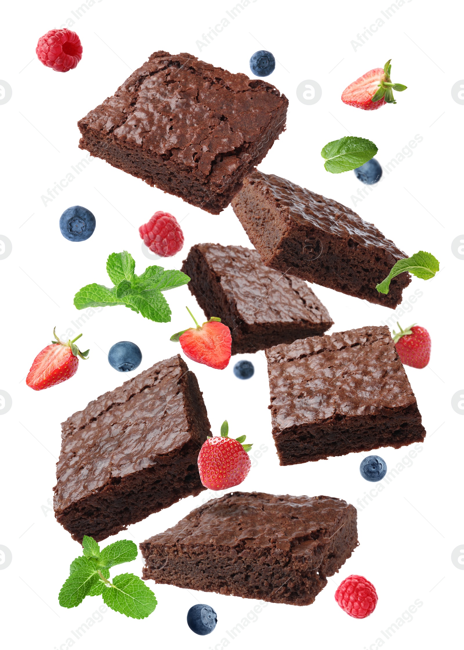 Image of Slices of delicious chocolate brownie with fresh berries and mint flying on white background