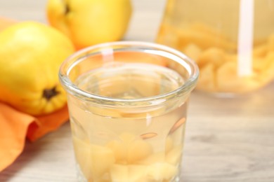 Photo of Delicious quince drink in glass and fresh fruits on table, closeup