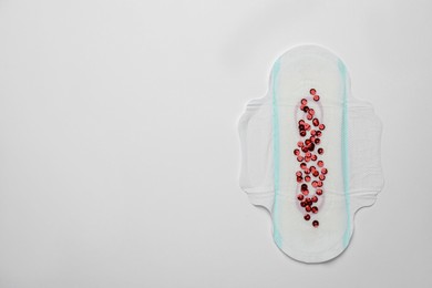 Photo of Menstrual pad with red sequins on white background, top view. Space for text