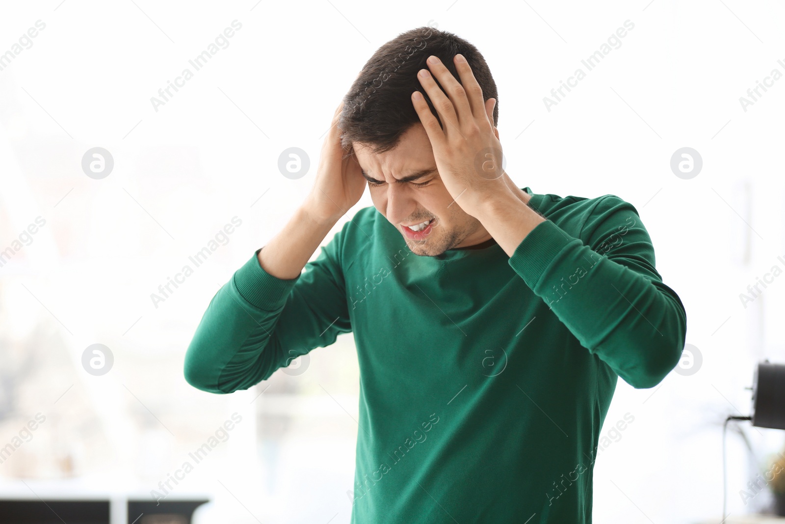 Photo of Young man suffering from headache at home