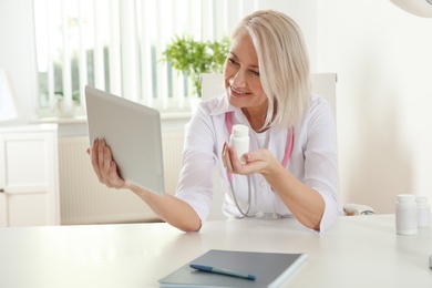 Photo of Doctor consulting patient using video chat on tablet in clinic