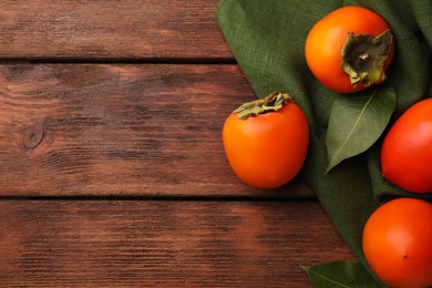 Photo of Delicious ripe persimmons on wooden table, flat lay. Space for text