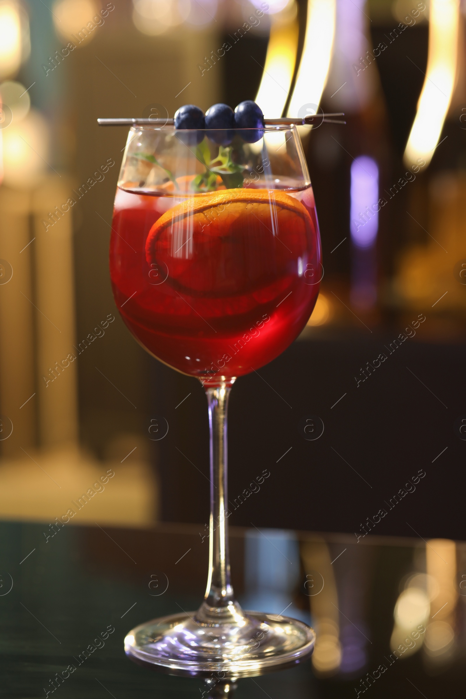 Photo of Glass of delicious refreshing sangria on table against blurred background