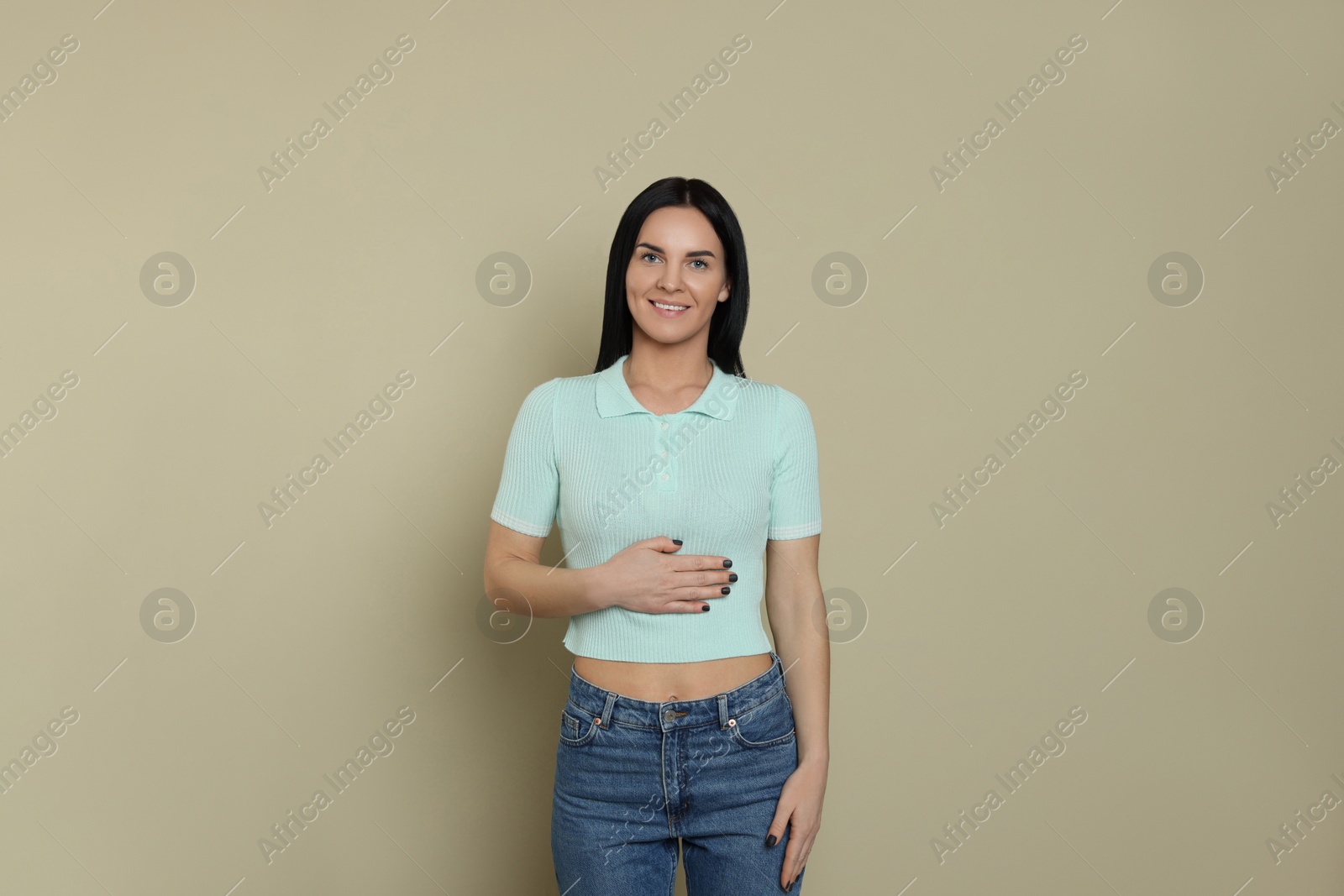 Photo of Happy woman touching her belly on beige background. Concept of healthy stomach