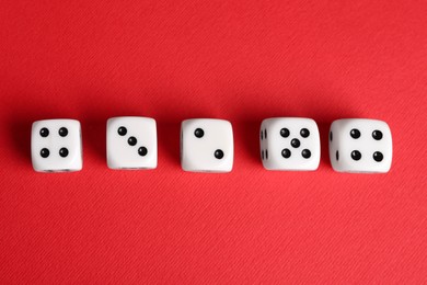Photo of Many white game dices on red background, flat lay