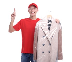 Dry-cleaning delivery. Happy courier holding coat in plastic bag and pointing at something on white background