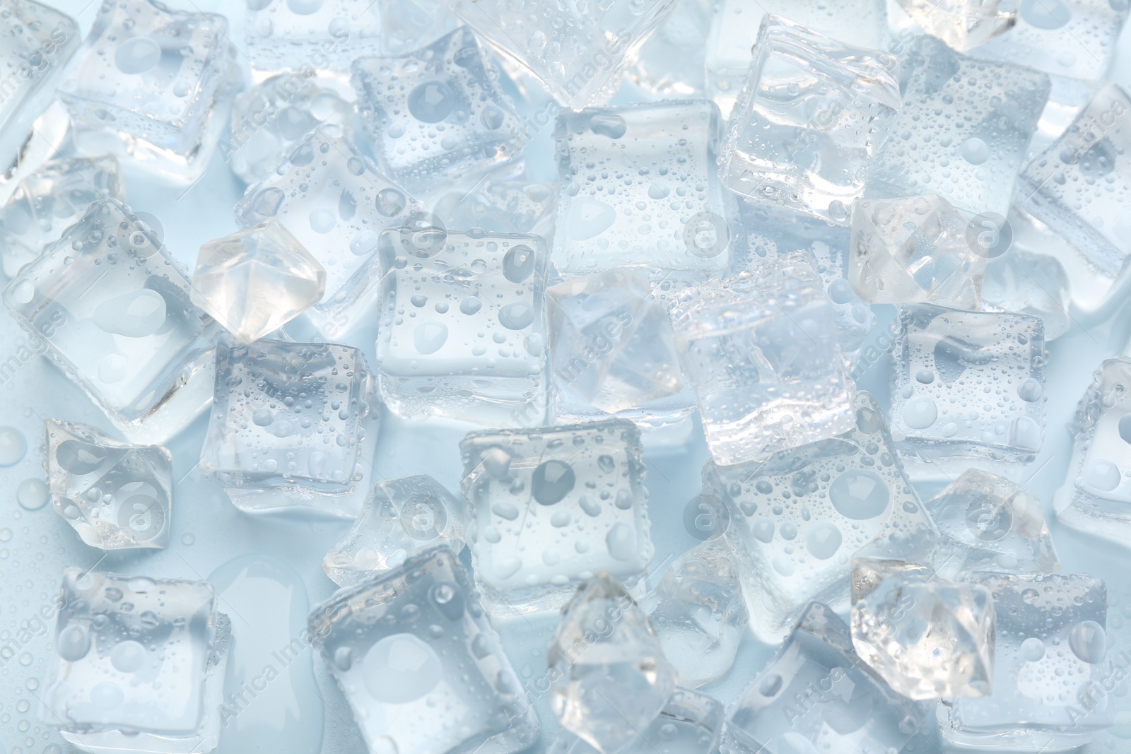 Photo of Crystal clear ice cubes on light blue background, flat lay