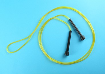 Skipping rope on light blue background, top view. Sports equipment