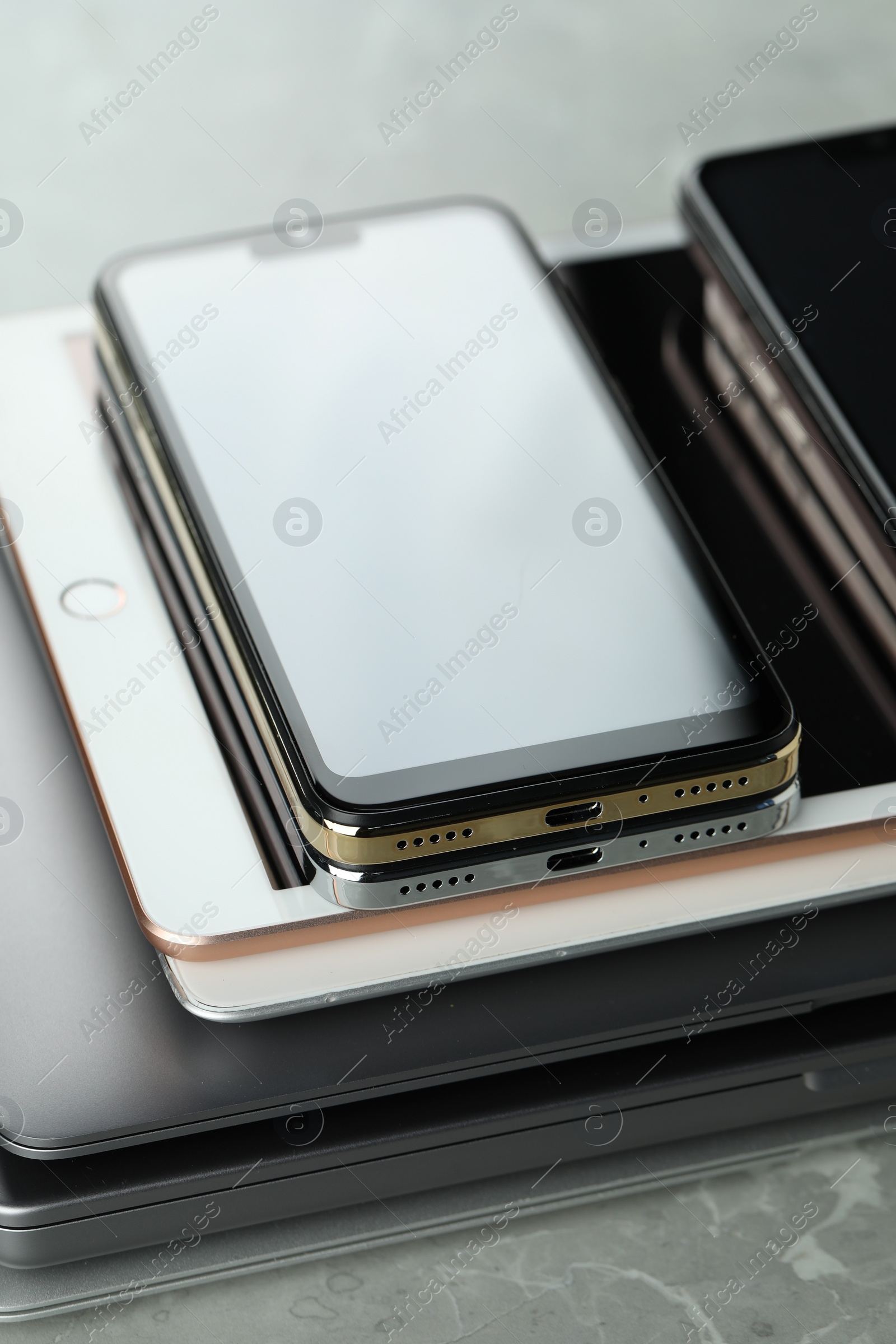 Photo of Stack of electronic devices on grey stone table, closeup