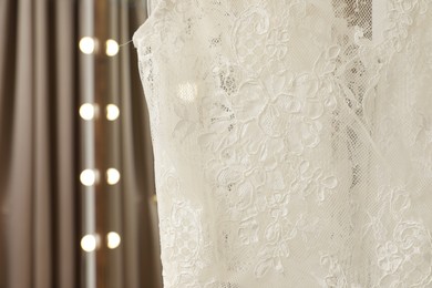 Photo of Beautiful wedding dress hanging in boutique, closeup