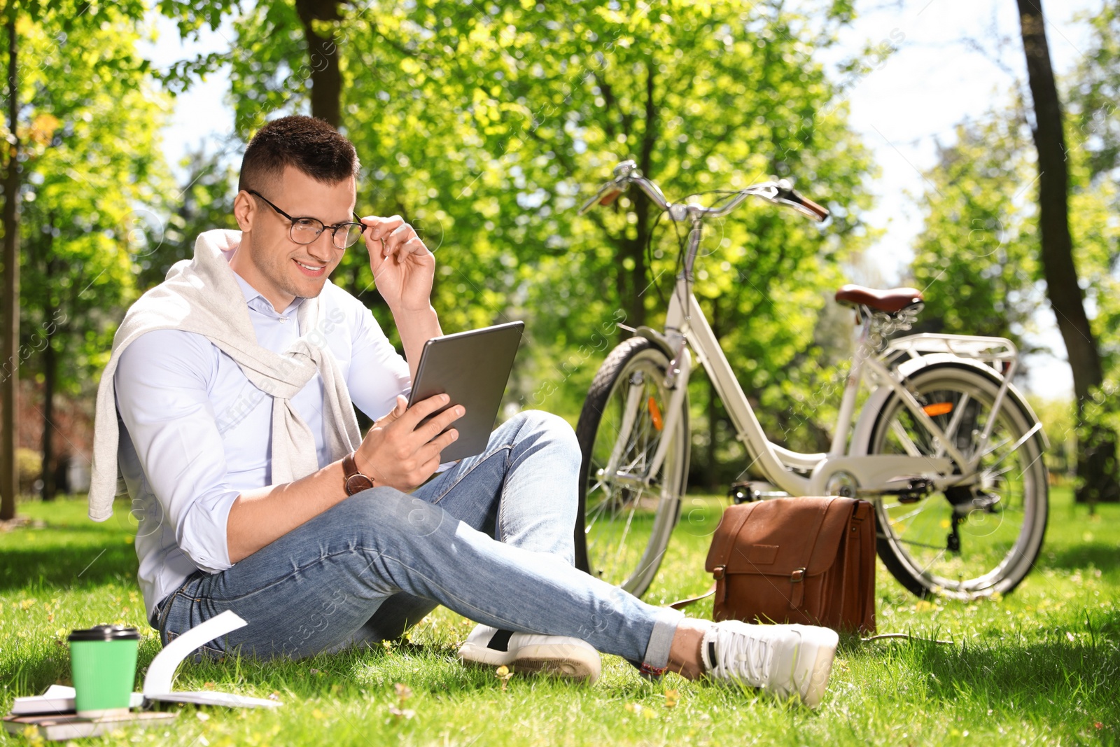 Photo of Man working with tablet on grass in park