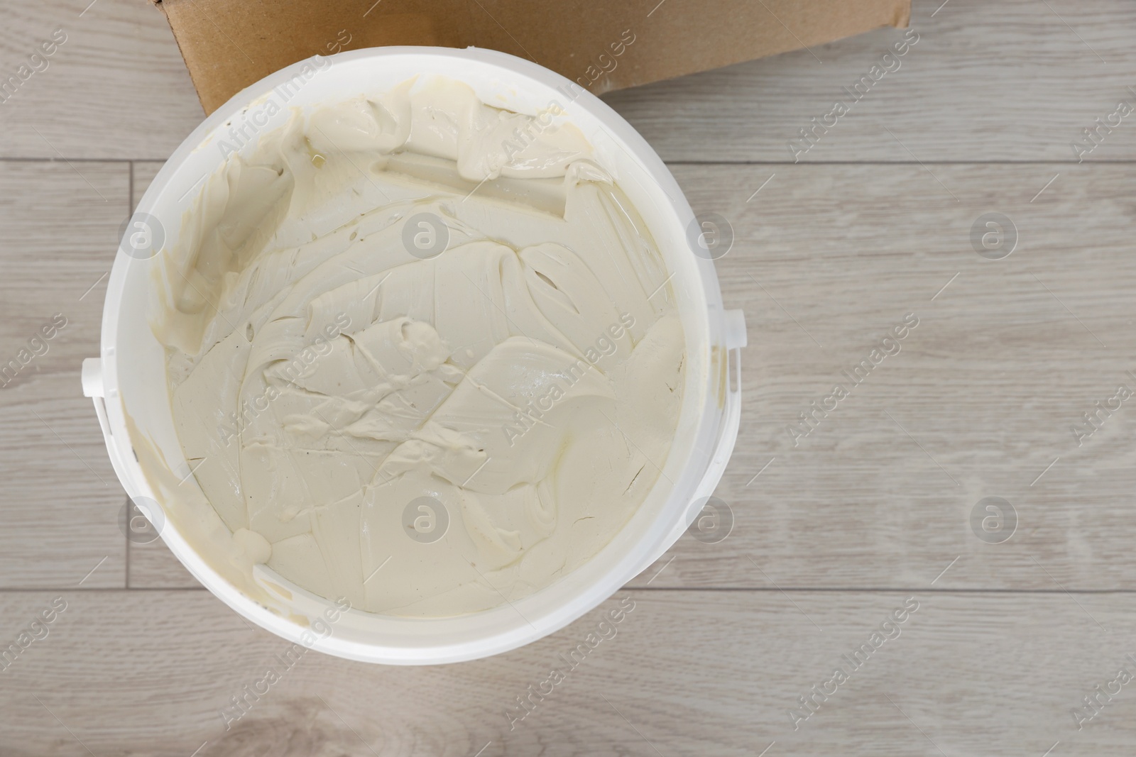 Photo of Bucket with plaster and putty knife on floor indoors, top view