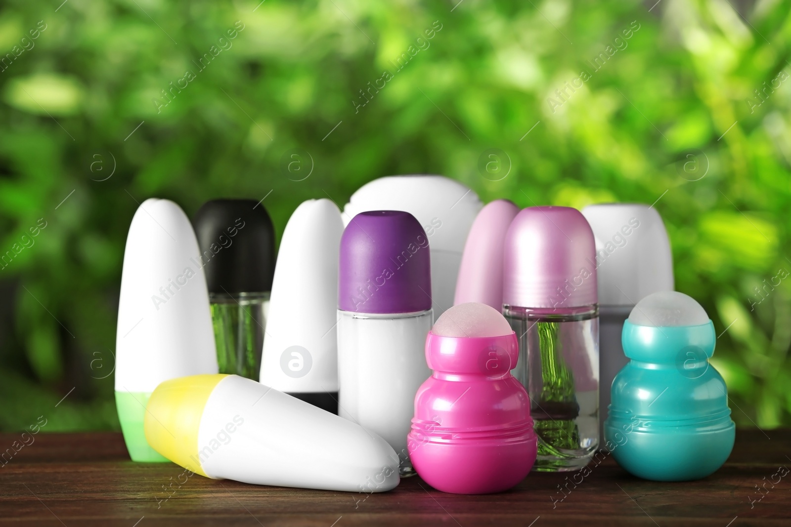 Photo of Set of different deodorants on wooden table against blurred green background