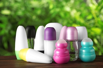 Photo of Set of different deodorants on wooden table against blurred green background