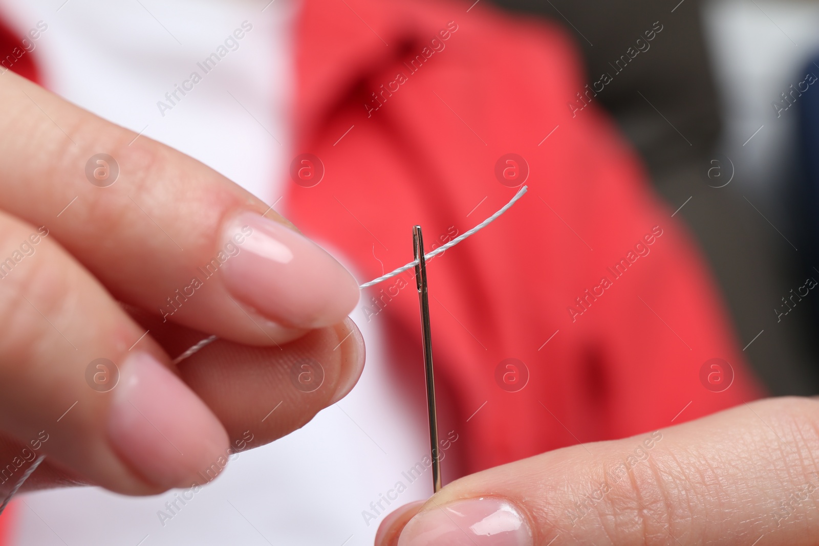 Photo of Woman inserting thread through eye of needle, closeup