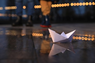 Photo of White paper boat in puddle on street