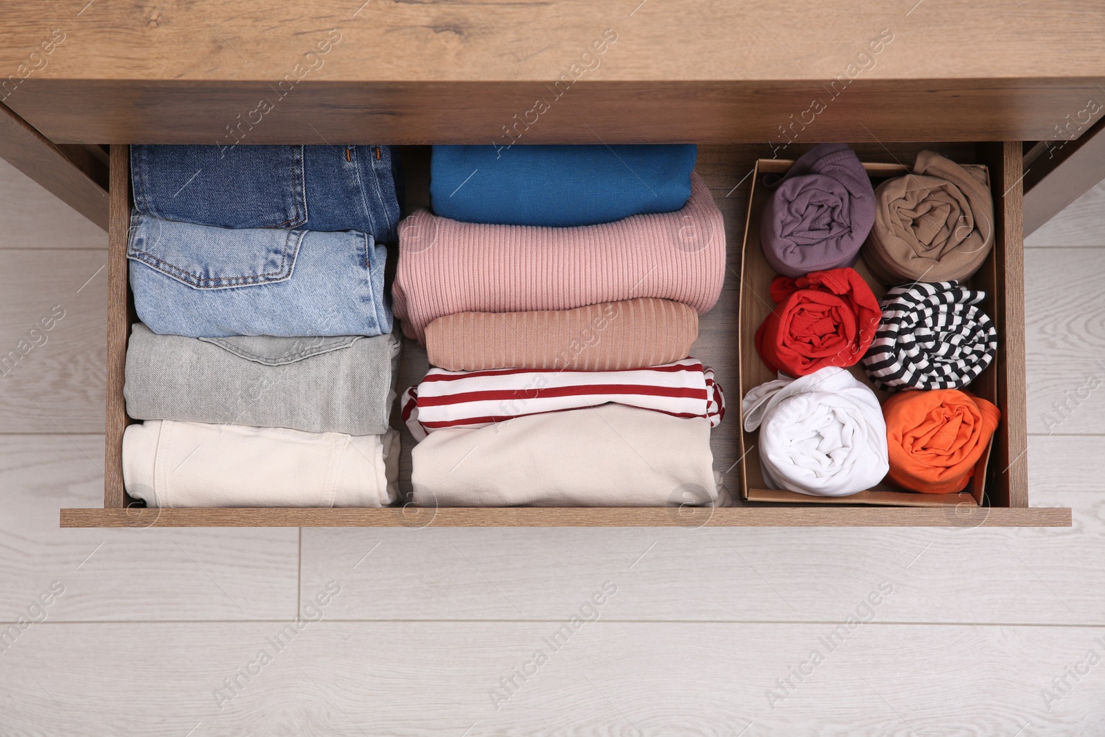 Photo of Open drawer with folded clothes indoors, top view. Vertical storage