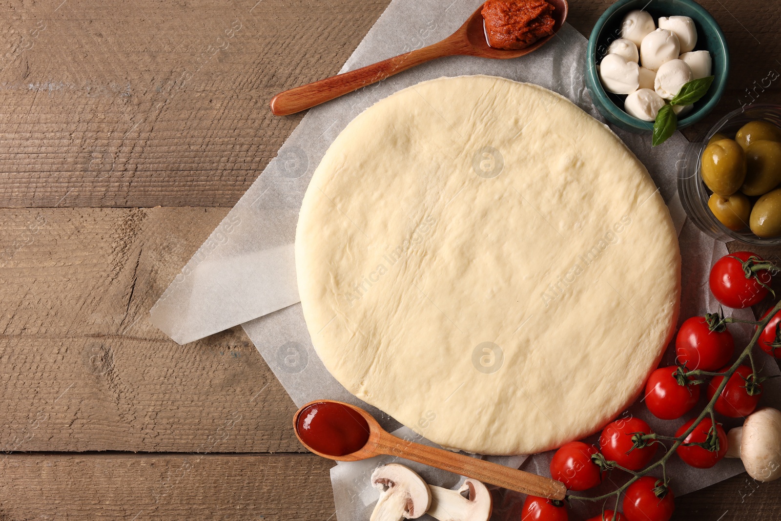 Photo of Pizza dough and products on wooden table, flat lay. Space for text