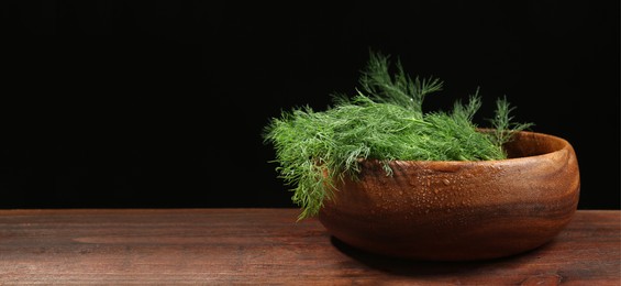 Image of Fresh dill in bowl on wooden table against black background. Banner design with space for text