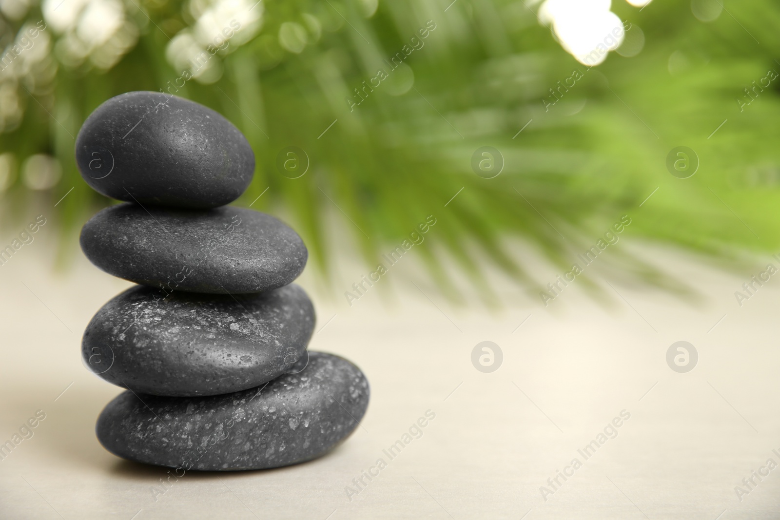 Photo of Stack of spa stones on table against blurred background. Space for text