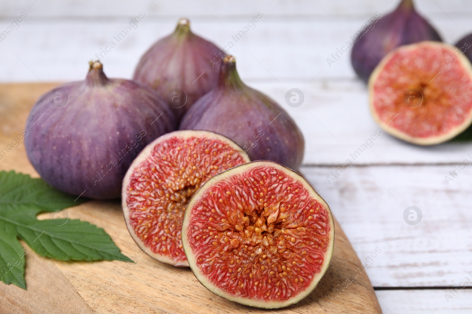 Photo of Fresh ripe figs on white wooden table, closeup. Space for text