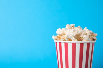 Photo of Delicious popcorn on light blue background, closeup. Space for text