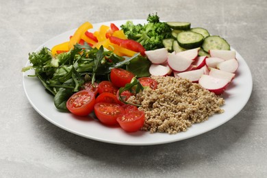 Photo of Vegetarian diet. Plate with tasty vegetables and quinoa on light grey table