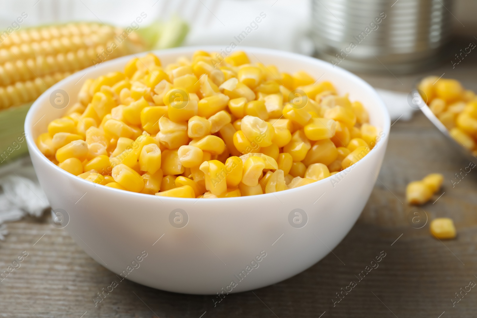 Photo of Bowl of preserved corn on wooden table, closeup